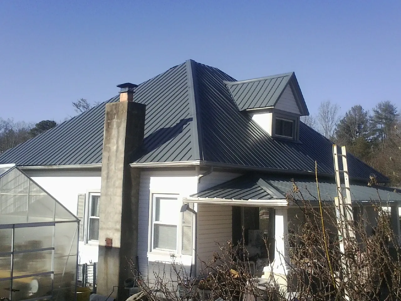 Dark blue standing seam metal roof on a white farmhouse with dormer — Slate & Tile Roof Repair by Roofing Brothers in Fostoria
