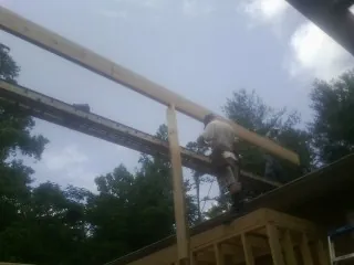 Carpenter setting a ridge beam over a new addition frame — Ice Dam Removal by Roofing Brothers in Fostoria