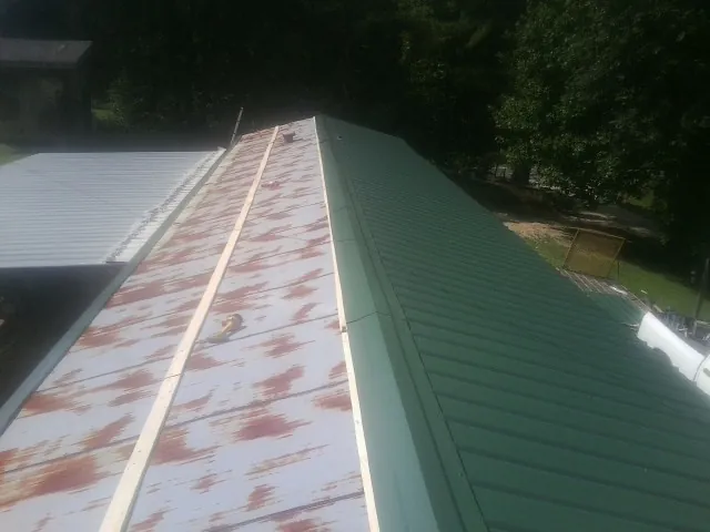 Old rusted panels beside newly installed green metal roofing — Wind Damage Roof Repair by Roofing Brothers in Fostoria