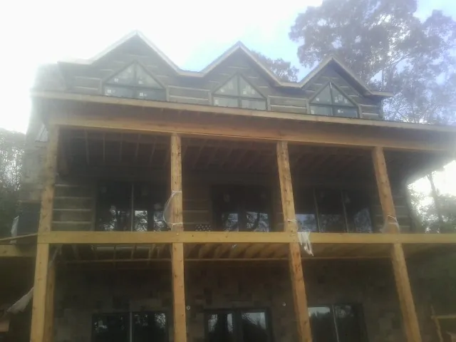 Dormers and porch framing on a large log home under construction — Roof Coating work by our crew in Fostoria