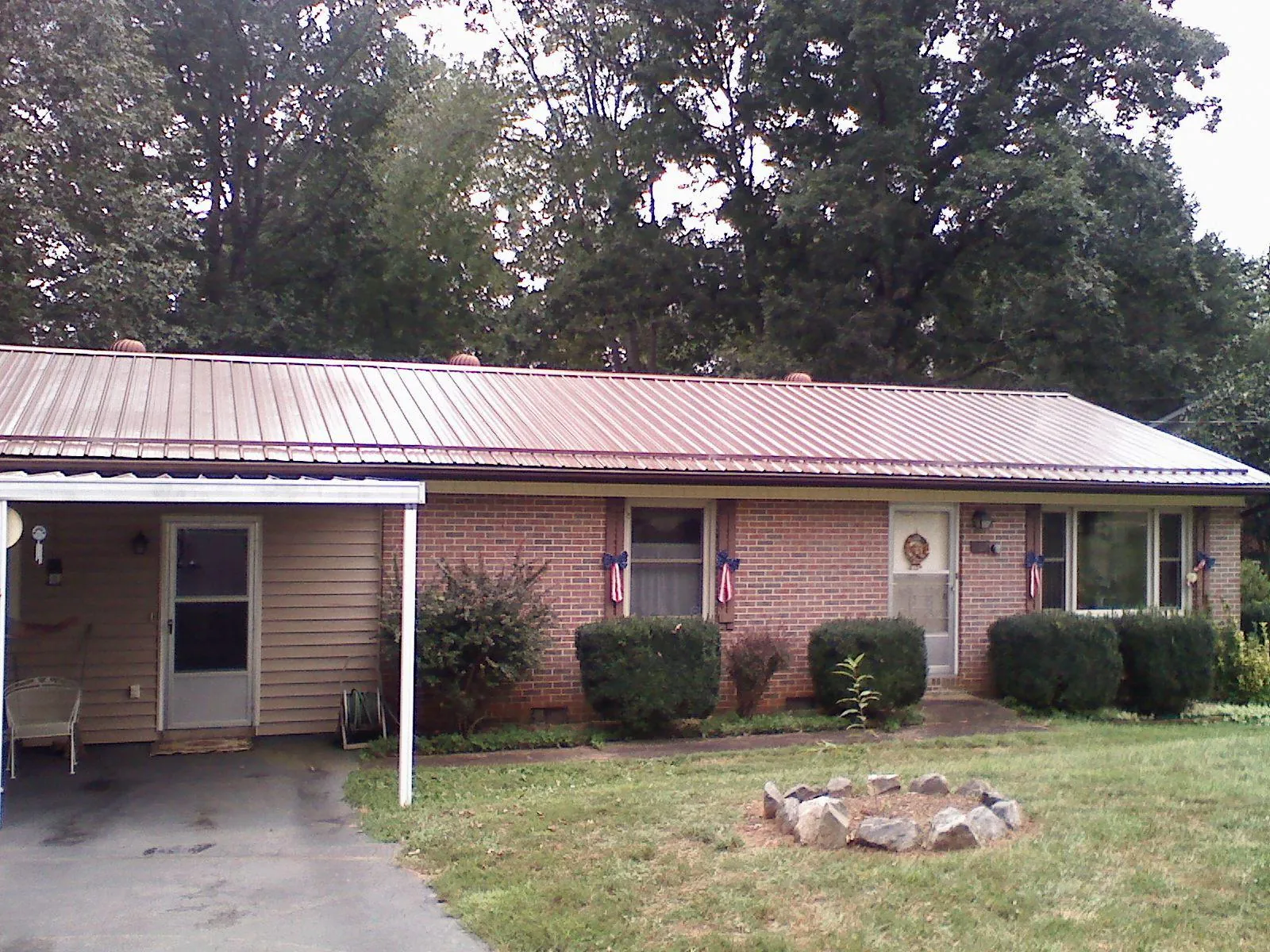 Bronze metal roof and carport on a brick ranch home — Roof Repair work by our crew in Fostoria