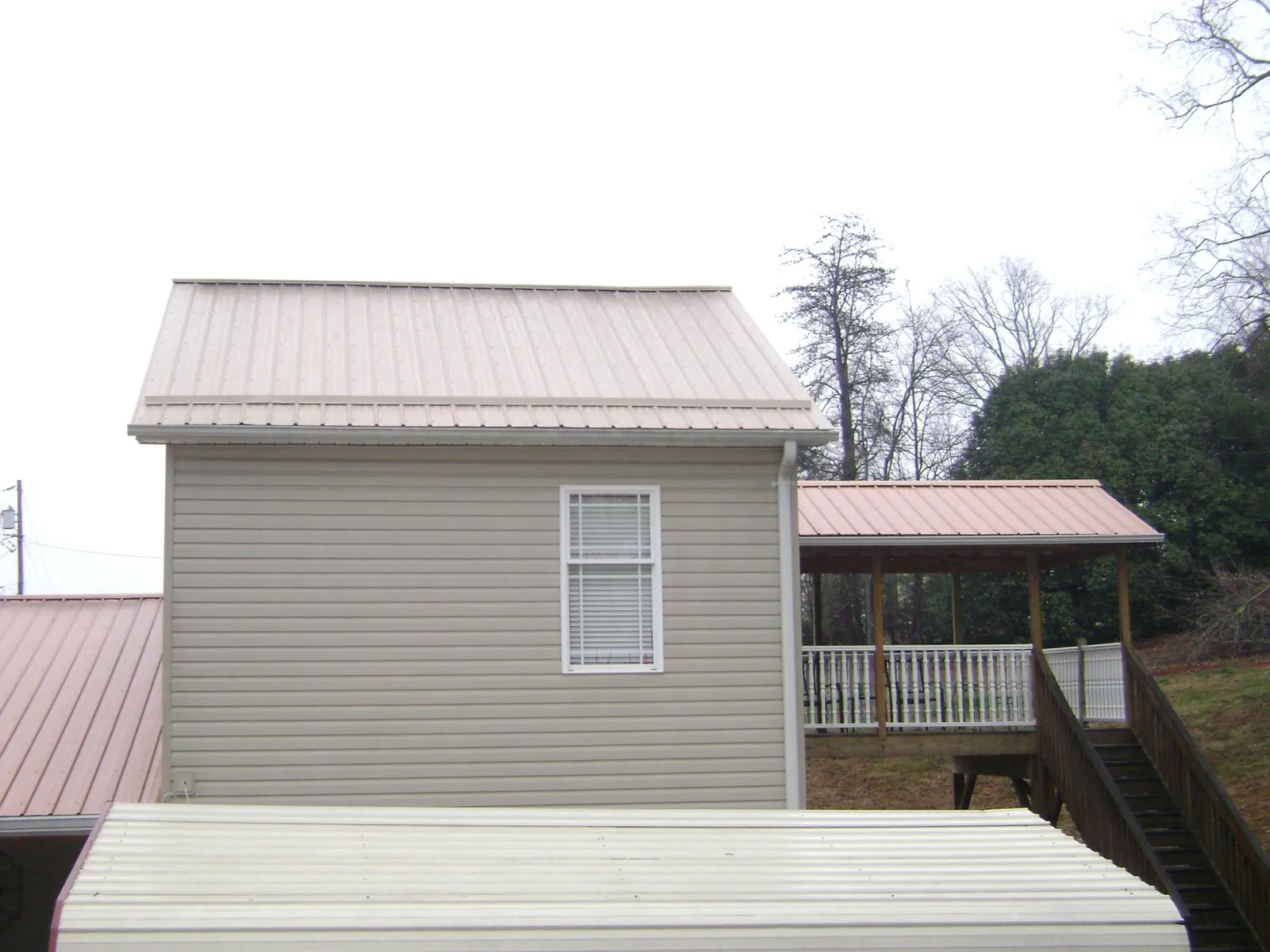 Tan metal roofs on a two story addition and attached porch, from a Roof Replacement job in Fostoria