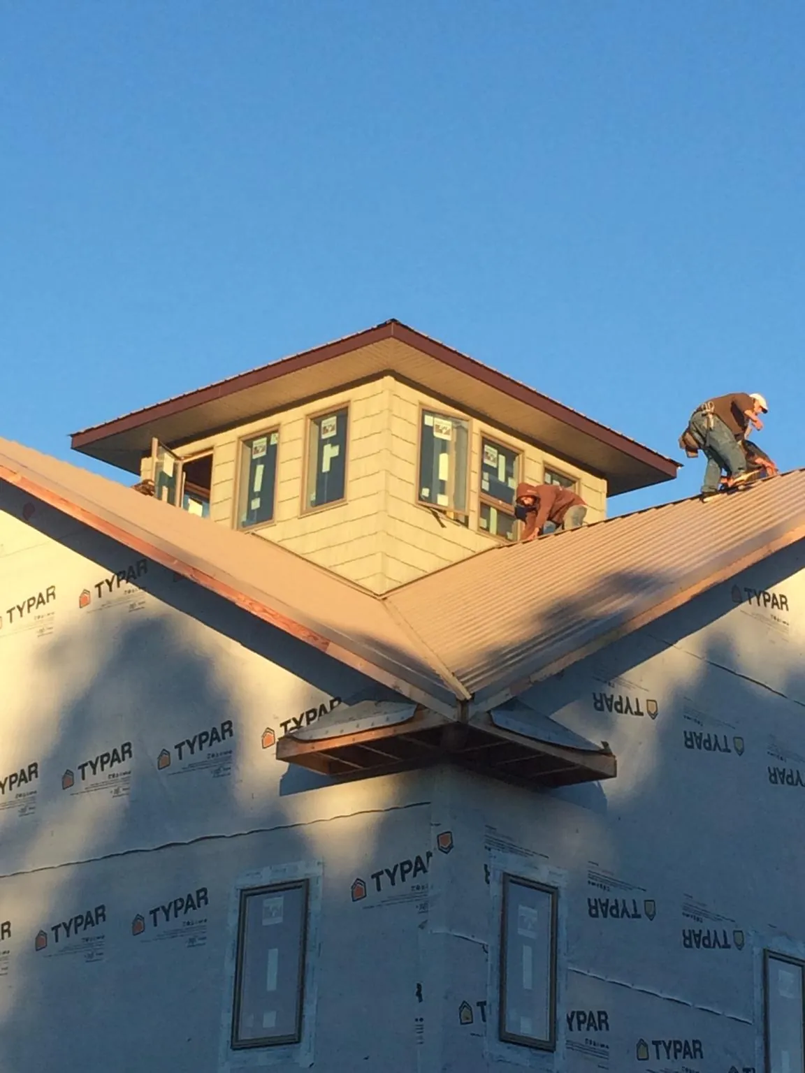 Roofers working around a rooftop cupola on a new metal roof at sunset — Roof Waterproofing in Fostoria by Roofing Brothers